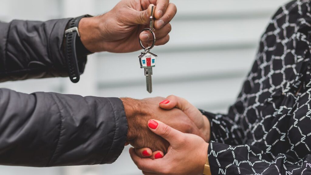 Two hands exchanging keys with a miniature house keychain, symbolizing the homebuying process facilitated by the National Association of Realtors.